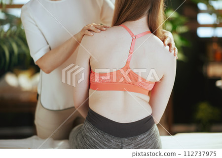 Female massage therapist checking back condition during checkup Female massage therapist checking back condition during checkup 112737975