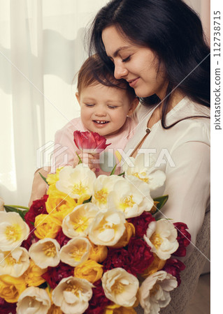 Cute little baby daughter and mom with flowers tulips. Mother and child hugging. Happy mother's day. Cute little baby daughter and mom with flowers tulips. Mother and child hugging. Happy mother's day. 112738715