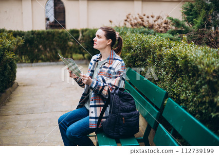 Beautiful stylish 30s woman in trendy wear spending time on street using paper map. Happy girl sitting on the bench. Urban lifestyle concept, travel banner 112739199