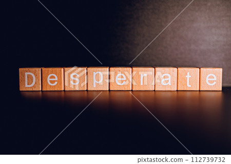 Wooden blocks form the text "Desperate" against a black background. 112739732