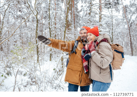 Man and woman in warm clothes spending time in a winter forest 112739771