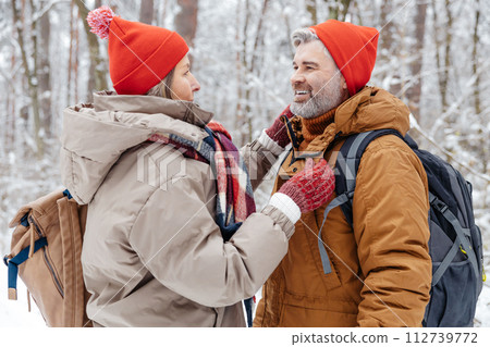 Man and woman in warm clothes spending time in a winter forest 112739772