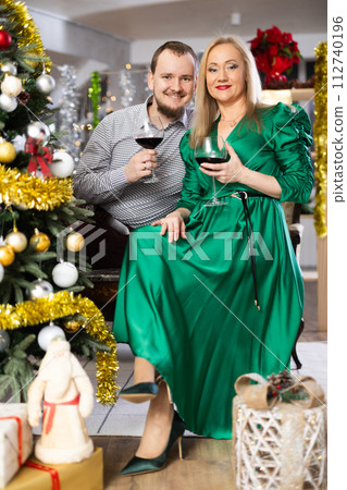 Husband and wife with glasses of red wine celebrate Christmas Husband and wife with glasses of red wine celebrate Christmas 112740196