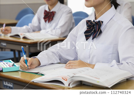 Hands of a high school girl in uniform studying in the classroom 112740324