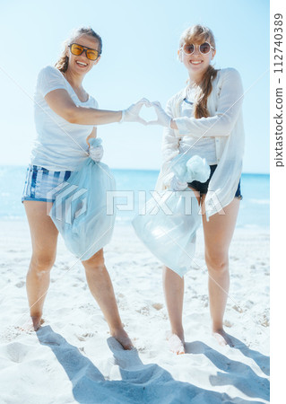 female volunteers collecting trash and showing heart hands 112740389