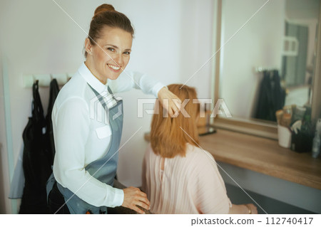 woman hairdresser in modern hair studio with client woman hairdresser in modern hair studio with client 112740417