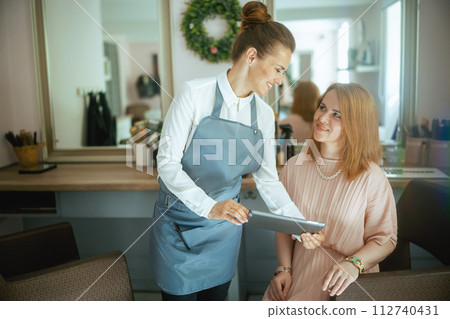 female hairdresser in modern beauty salon with tablet PC female hairdresser in modern beauty salon with tablet PC 112740431