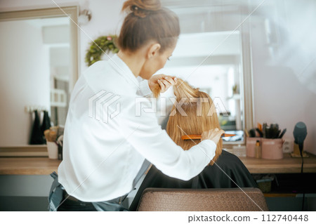Seen from behind woman hairdresser in modern beauty salon 112740448