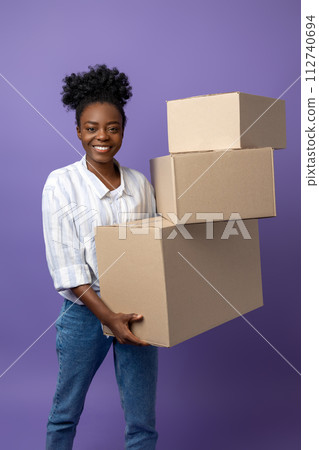 Dark-skinned young woman with boxes in hands looking contented Dark-skinned young woman with boxes in hands looking contented 112740694