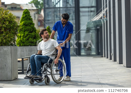 Brunette male nurse rolling a wheelchair with a patient 112740706
