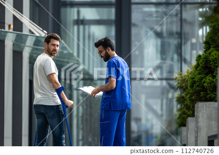 Brunette male nurse and his patient having a walk together 112740726