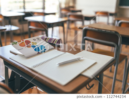 Textbooks and notebooks placed on classroom desks Textbooks and notebooks placed on classroom desks 112744234