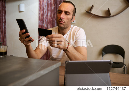 Young businessman freelancer receives payment, checks balance on mobile app, orders food, booking tickets on internet 112744487