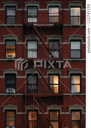 Charming New York Architecture with Fire Escapes and Lit Windows 112745159
