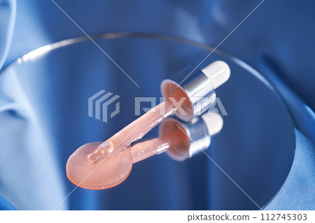 Bottle with pink serum on a blue background. 112745303