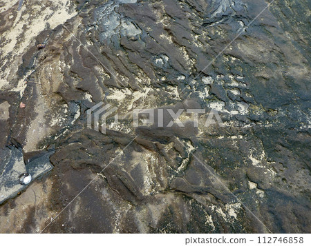 Cracked weathered Lava rock with bits of sand and puddles of water Cracked weathered Lava rock with bits of sand and puddles of water 112746858