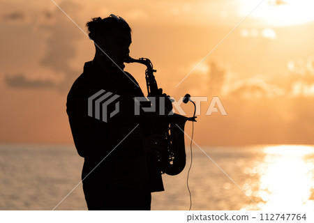 Man playing the Saxophone at sunset 112747764