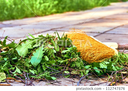 Yellow plastic mop sweeping trash in the yard Yellow plastic mop sweeping trash in the yard 112747876