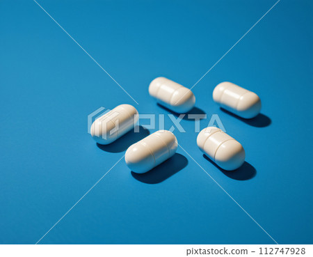 Close-up of a set of white pills on a blue background 112747928