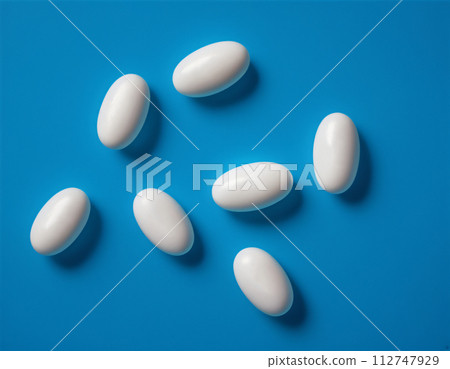 Close-up of a set of white pills on a blue background 112747929