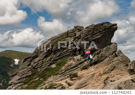 Mother and daughter are climbed high on a rocky stone located on Mount Ukhaty Kamin. 112748261