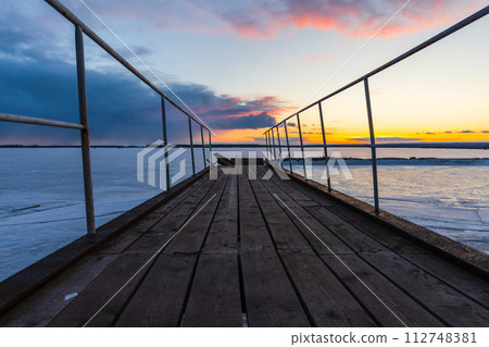 Perspective view of an abandoned broken pier under sunset sky 112748381