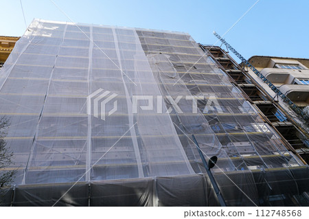 Gray safety net around a large city house facade during reconstruction, grey protective coating 112748568