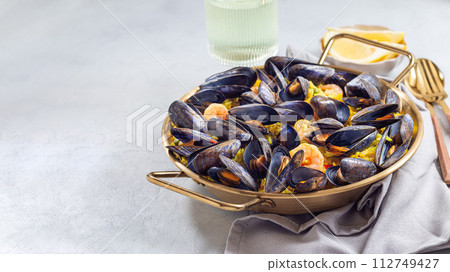 Seafood paella with mussels and shrimps in traditional plate, horizontal, copy space 112749427