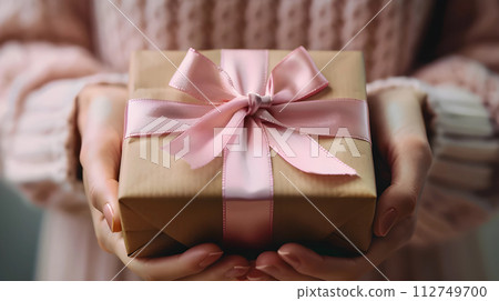 AI-generated content. Hands holding gift box wrapped and decorated with satin ribbon, generated AI 112749700