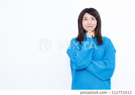 A woman wearing a blue hoodie smiling and thinking 112751011