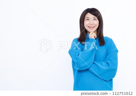 A woman wearing a blue hoodie smiling and thinking 112751012