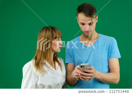 Picture of a young couple watching a funny video on mobile phone, posing on isolated background. High quality photo Picture of a young couple watching a funny video on mobile phone, posing on isolated background. High quality photo 112751448