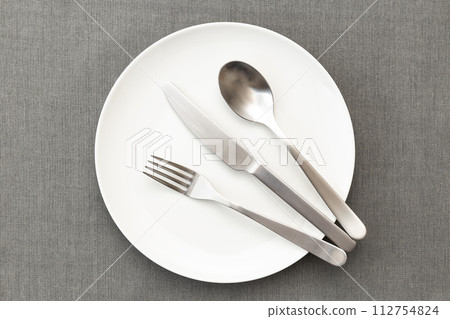 White plates and cutlery on place mat White plates and cutlery on place mat 112754824