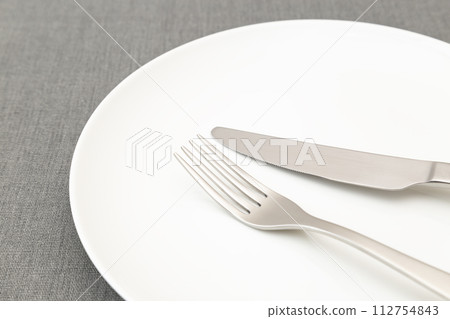White plates and cutlery on place mat 112754843
