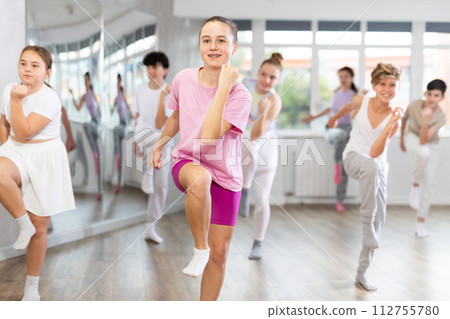 Woman teacher in background dances with students, inspects and observes skill of dancers 112755780