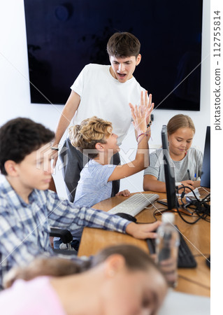 Teacher giving high five to boy student in classroom 112755814