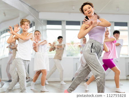 Group of teens performs modern dances with female teacher during class at choreographic school. 112755828