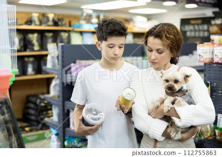 Teenager with mother and Yorkshire terrier choosing dog food in store Teenager with mother and Yorkshire terrier choosing dog food in store 112755863