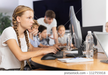 Preteen girl working with computer programs in training room Preteen girl working with computer programs in training room 112755918