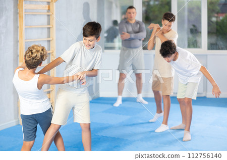 Diligent preteen student practicing self-defense techniques in pairs Diligent preteen student practicing self-defense techniques in pairs 112756140