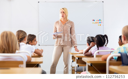 Woman teacher standing at whiteboard during lesson with tweens Woman teacher standing at whiteboard during lesson with tweens 112756253