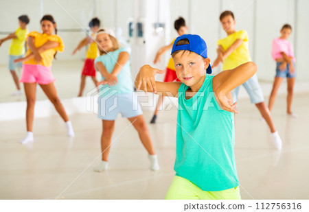 Preteen boy in blue cap learning hip-hop during group dance lesson 112756316