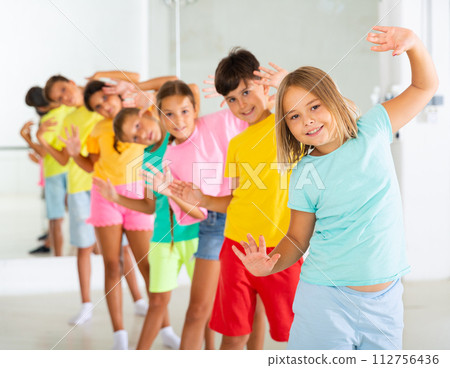 Group of children rehearsing movements of ballet in classroom 112756436