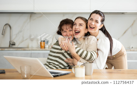 Three happy middle-aged woman expressing joy for winning in the kitchen 112756437