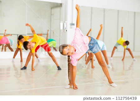 Sporty ten years old girl doing stretching warm-up in dance class 112756439