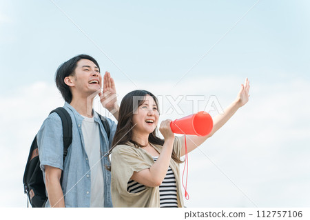 藍天下年輕的亞洲男女透過擴音器歡呼、歡呼、歡呼 112757106