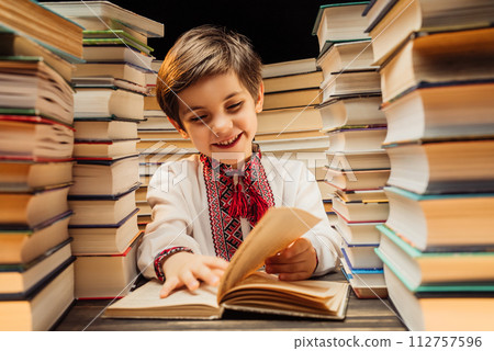 Handsome little ukrainian child flips through book pages in library. Elementary school boy enjoying Handsome little ukrainian child flips through book pages in library. Elementary school boy enjoying 112757596