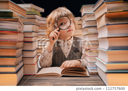 Little researcher boy reads book with magnifying glass in library. Cute clever preschooler playing Little researcher boy reads book with magnifying glass in library. Cute clever preschooler playing 112757600