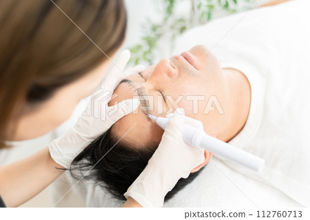 Permanent makeup marking, design, eyebrow salon, men's eyebrow salon, man adjusting eyebrows at beauty eyebrow salon Permanent makeup marking, design, eyebrow salon, men's eyebrow salon, man adjusting eyebrows at beauty eyebrow salon 112760713