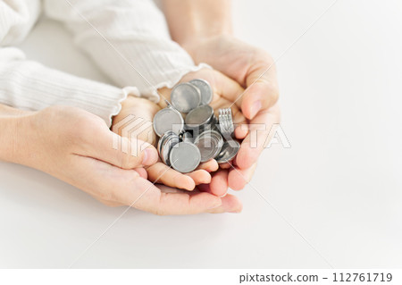 Parent and child's hands placing a coin Parent and child's hands placing a coin 112761719